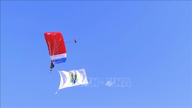 Màn nhảy dù từ độ cao 2.000m xuống sân vận động quốc gia ở thủ đô Viêng Chăn (Lào) của 1 chiến sĩ mang theo cờ có hình linh vật  là hình chim công tại lễ khai mạc. Ảnh: Đỗ Bá Thành - PV TTXVN tại Lào