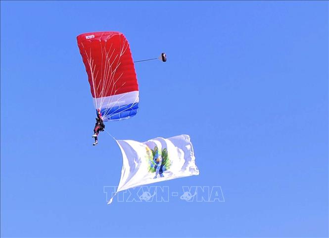Màn nhảy dù từ độ cao 2.000m xuống sân vận động quốc gia ở thủ đô Viêng Chăn (Lào) của 1 chiến sĩ mang theo cờ có hình linh vật  là hình chim công tại lễ khai mạc, Ảnh: Đỗ Bá Thành - PV TTXVN tại Lào
