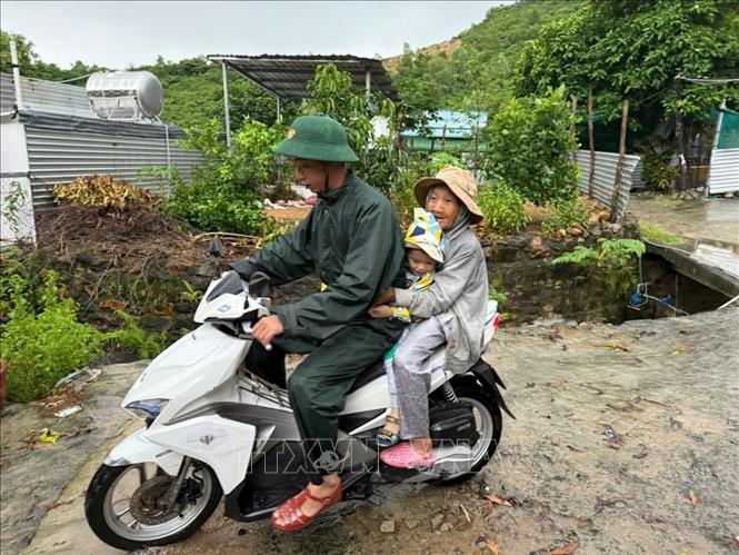 Lực lượng chức năng hỗ trợ người dân khu vực Xóm Núi (tổ dân phố Thành Phát, phường Nam Nha Trang) di chuyển đến nơi an toàn. Ảnh: TTXVN phát