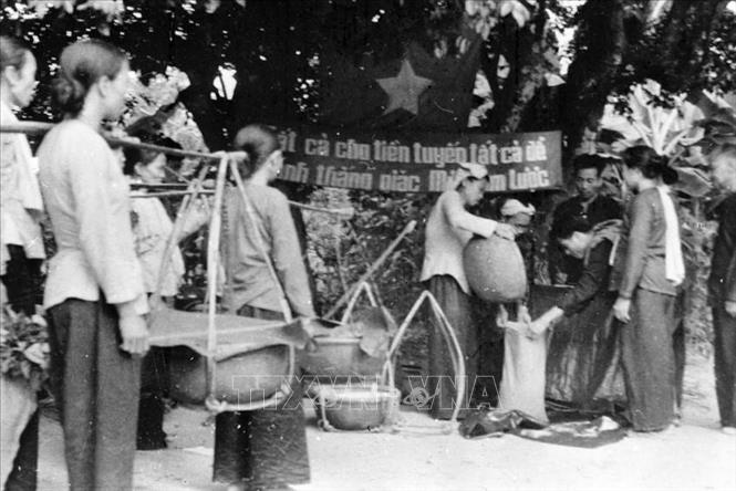 Trong những năm đấu tranh chống đế quốc Mỹ và bè lũ tay sai, Mặt trận Tổ quốc Việt Nam đã ra sức vận động các tầng lớp Nhân dân thi đua yêu nước, tham gia khôi phục kinh tế và phát triển văn hóa, hàn gắn vết thương chiến tranh, cải tạo và xây dựng miền Bắc xã hội chủ nghĩa thực sự là cơ sở vững chắc cho cuộc đấu tranh thống nhất nước nhà. Trong ảnh: Chị em phụ nữ xã Thanh An (Bến Cát, Thủ Dầu Một) đóng góp lương thực, tiền bạc cho quỹ kháng chiến chống Mỹ (1968). Ảnh: Hoàng Vinh - TTXVN