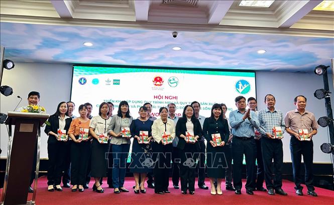 Thứ trưởng Bộ Nông nghiệp và Môi trường Trần Thanh Nam trao sổ tay hướng dẫn Quy trình ký thuật sản xuất lúa chất lượng cao, phát thải thấp và Quy trình MRV. Ảnh: Thu Hiền - TTXVN