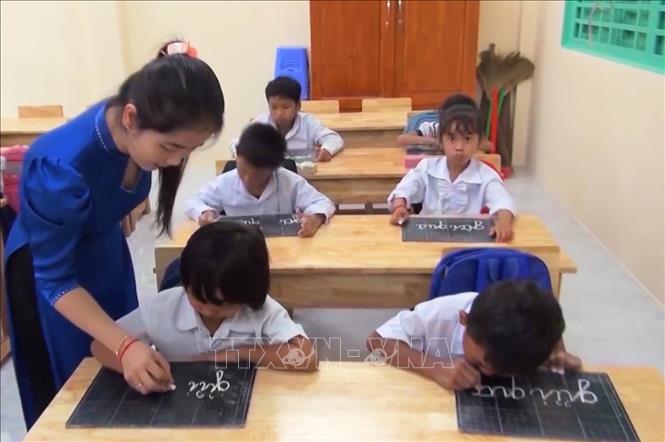 Cô giáo Nèang Lai My hướng dẫn từng học sinh cách cầm phấn để viết chữ. Ảnh: Công Mạo-TTXVN