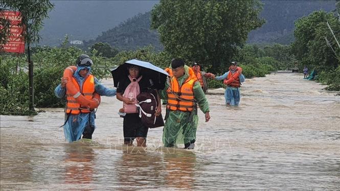 Lực lượng chức năng hỗ trợ sơ tán người dân khu vực phường Nam Nha Trang (Khánh Hòa) đến nơi an toàn. Ảnh: TTXVN phát