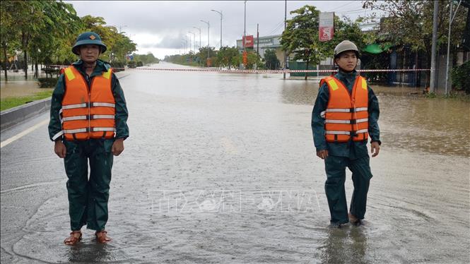 Lực lượng chức năng túc trực tại khu vực ngập sâu trên đường Võ Nguyên Giáp (xã Diên Khánh) để hướng dẫn, đảm bảo an toàn cho người dân và phương tiện. Ảnh: Nguyễn Thành - TTXVN