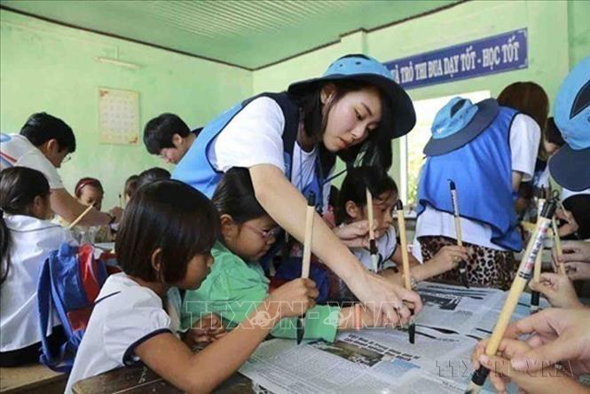 Tình nguyện viên Đại học Chung-Ang, Seoul (Hàn Quốc) hướng dẫn học sinh trường Tiểu học An Hải 1 (huyện đảo Lý Sơn, tỉnh Quảng Ngãi) viết thư pháp. Ảnh: Sỹ Thắng - TTXVN