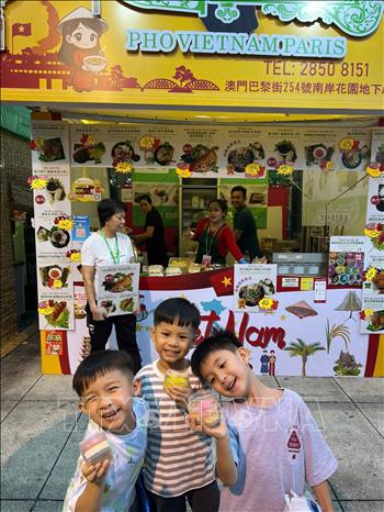 Trẻ em thích thú với món ăn thạch vừa mua được tại gian hàng ẩm thực Việt Nam.   Ảnh: TTXVN phát