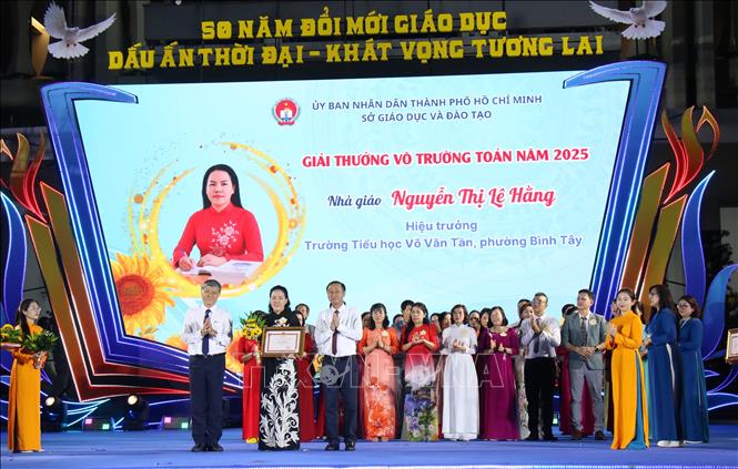 Ông Nguyễn Văn Hiếu, Phó Giám đốc Sở Giáo dục và Đào tạo Thành phố Hồ Chí Minh và ông Huỳnh Thanh Nhân, Phó chủ tịch HĐND Thành phố Hồ Chí Minh trao giải thưởng cho cô giáo Nguyễn Thị Lê Hằng. Ảnh: Thu Hương - TTXVN