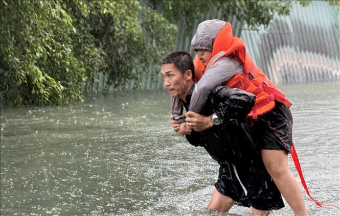 Di dời một trẻ em đến nơi an toàn. Ảnh: Tường Quân - TTXVN