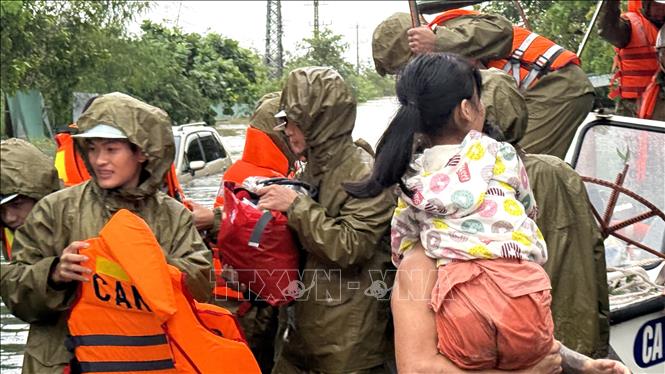 Cứu giúp trẻ em và di dời đồ đạt cho người dân. Ảnh: Tường Quân - TTXVN