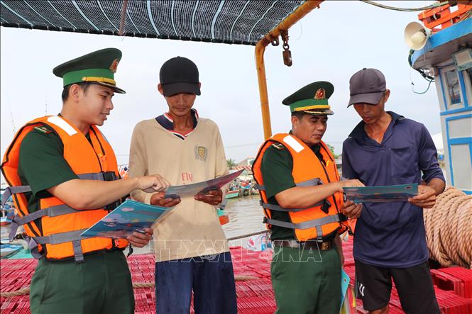 Chiến sĩ Đồn Biên phòng Long Vĩnh tuyên truyền chống khai thác IUU cho ngư dân tại Cảng cá Định An (xã Đại An, tỉnh Vĩnh Long). Ảnh: Thanh Hòa- TTXVN