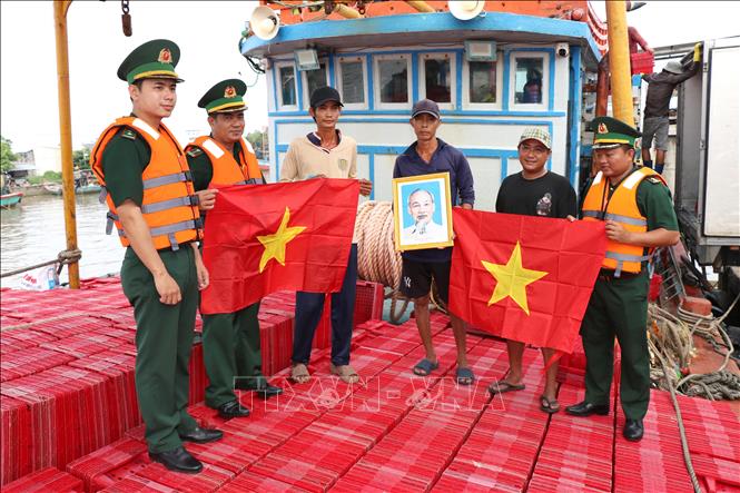 Chiến sĩ Đồn Biên phòng Long Vĩnh tặng cờ Tổ quốc và ảnh Bác Hồ cho ngư dân tại Cảng cá Định An (xã Đại An, tỉnh Vĩnh Long). Ảnh: Thanh Hòa- TTXVN