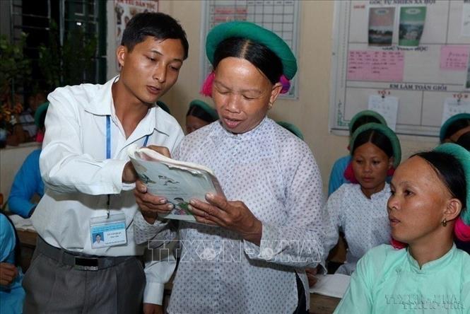 Thầy giáo tận tình hướng dẫn học viên người dân tộc tập đọc tại lớp học xóa mù chữ ở tỉnh Quảng Ninh. Ảnh: Quý Trung - TTXVN