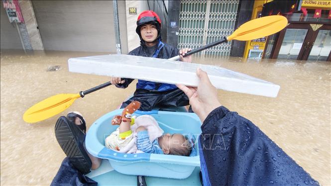 Hỗ trợ sơ tán trẻ em trong khu dân cư bị ngập lụt ở phường Tây Nha Trang (Khánh Hòa). Ảnh: Nguyễn Thành - TTXVN