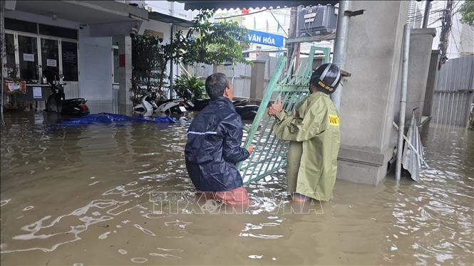 Chính quyền hỗ trợ người dân khắc phục ngập lụt. Ảnh: Đặng Tuấn – TTXVN

