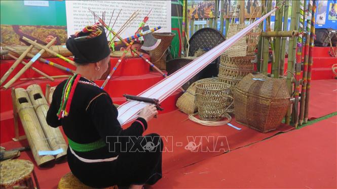 Nghệ nhân người Khơ Mú bên khung cửi dệt túi. Ảnh: Hương Thu-TTXVN                          