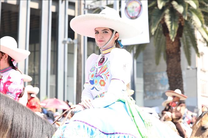 Cô gái trong bộ quần áo truyền thống của Mexico cưỡi ngựa diễu hành trên đường phố. Ảnh: Phi Hùng - PV TTXVN tại Mexico