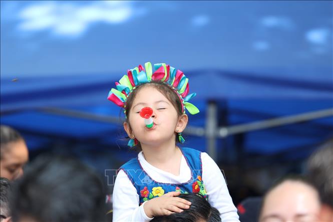 Bé gái Mexico thổi kèn chào đón đoàn diễu hành. Ảnh: Phi Hùng - PV TTXVN tại Mexico