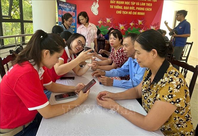 Hướng dẫn người dân phường Tây Tựu triển khai các dịch vụ công trực tuyến. Ảnh: Nguyễn Cúc-TTXVN