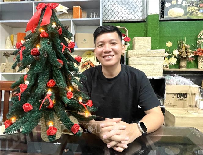 Anh Đỗ Đăng Khoa, chủ dự án “Làng mướp” cùng với cây thông Noel trang trí bằng cơ mướp. Ảnh: Hồng Nhung - TTXVN 
