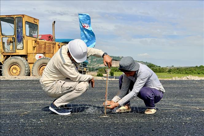 Công nhân canh tim đường và cao độ để thảm bê tông nhựa tuyến chính. Ảnh: Thanh Sang-TTXVN