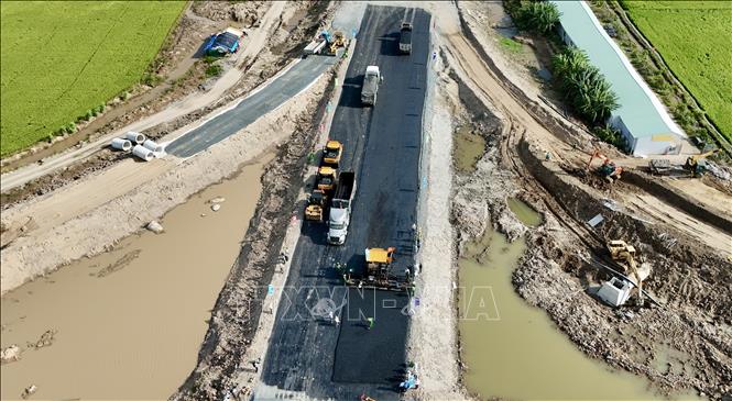 Nhà thầu Trường Sơn huy động nhiều thiết bị hiện đại thi công thảm nhựa trong chiều 21/11. Ảnh: Thanh Sang-TTXVN