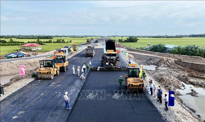 Dòng phương tiện thi công nối tiếp nhau tạo thành dây chuyền thảm nhựa liên tục. Ảnh: Thanh Sang-TTXVN
