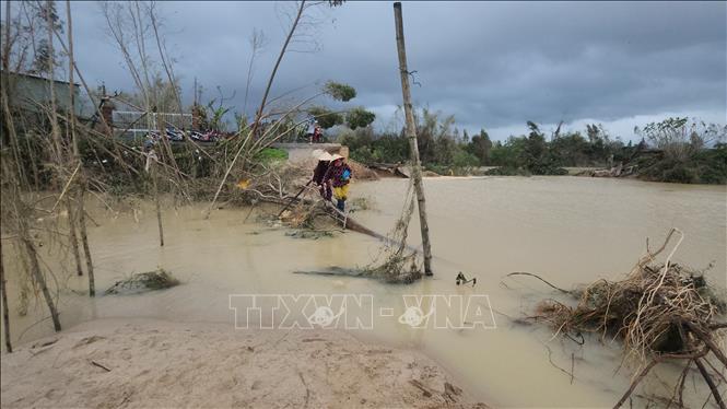 Người dân phải đi đường vòng phía hạ du để nhận lương thực sau khi nước rút. Ảnh: Sỹ Thắng-TTXVN