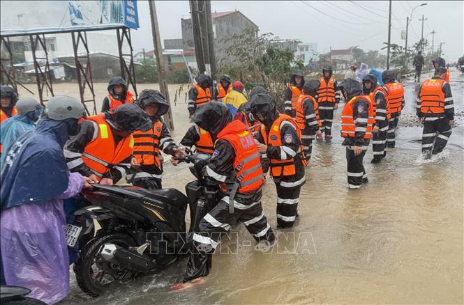 Cán bộ, chiến sỹ hỗ trợ người dân xã Hoà Thịnh di chuyển qua đoạn đường hư hại do mưa lũ.  Ảnh: Tường Quân - TTXVN
