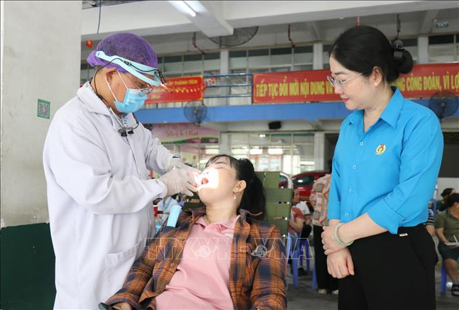 Bà Nguyễn Kim Loan, Phó Chủ tịch Liên đoàn Lao động Thành phố Hồ Chí Minh thăm hỏi công nhân và các y bác sỹ tình nguyện khám và điều trị răng miễn phí cho công nhân lao động tại ngày hội. Ảnh: Thanh Vũ-TTXVN
