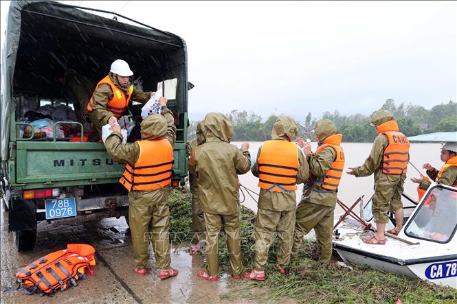 Lực lượng Công an tỉnh Đắk Lắk tiếp tế lương thực lên cano để di chuyển vào vùng dân cư ngập sâu ven sông Bánh Lái. Ảnh: Đỗ Trưởng – TTXVN