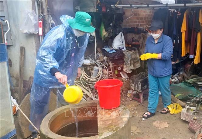  Cán bộ y tế Gia Lai khử khuẩn hệ thống giếng nước cho người dân vùng lũ. Ảnh: Quang Thái- TTXVN