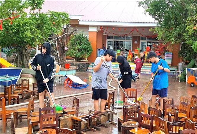 Người dân cùng lực lượng chức năng dọn vệ sinh tại Làng trẻ em SOS Quy Nhơn sau bão lũ. Ảnh: Quang Thái- TTXVN