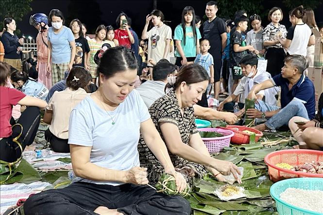 Trong đêm khuya, hàng trăm người dân phường Trảng Dài (tỉnh Đồng Nai) cần mẫn gói từng chiếc bánh để gửi tới đồng bào vùng lũ. Ảnh: Lê Xuân-TTXVN