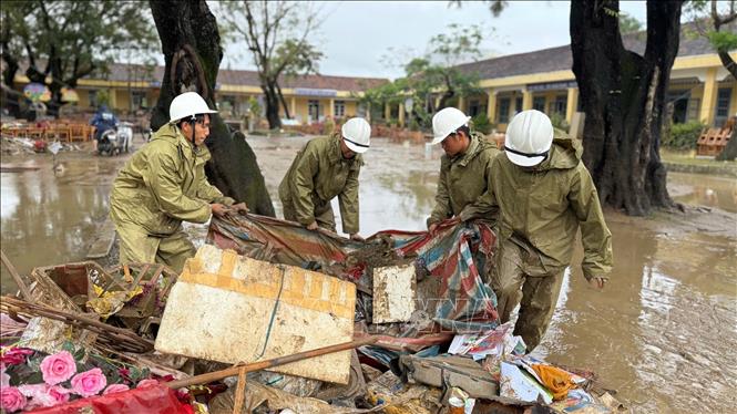 Lực lượng Quân đội hỗ trợ người dân thu dọn rác và bùn đất sau khi nước rút. Ảnh: Nguyên Dung – TTXVN