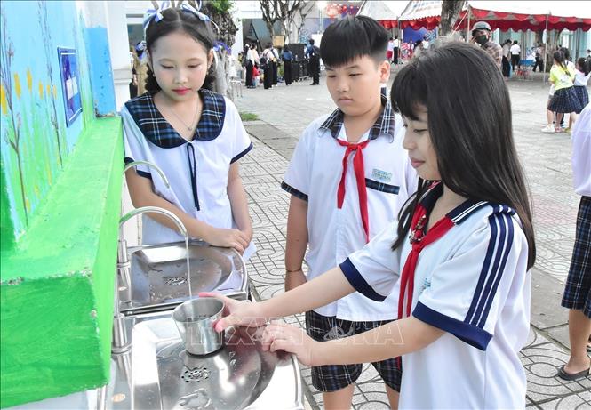 Học sinh Trường Tiểu học Trần Văn Ẩn ở phường Long Đức (Vĩnh Long) sử dụng nguồn nước uống từ hệ thống lọc nước RO năng lượng mặt trời do Chương trình hỗ trợ. Ảnh: Thanh Hòa- TTXVN