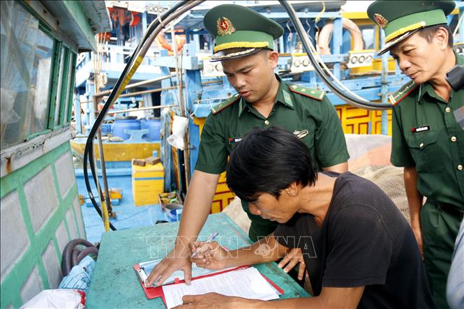 Cán bộ Đồn Biên phòng Thanh Hải hướng dẫn ngư dân ký cam kết không vi phạm IUU. Ảnh: Hồng Hiếu - TTXVN