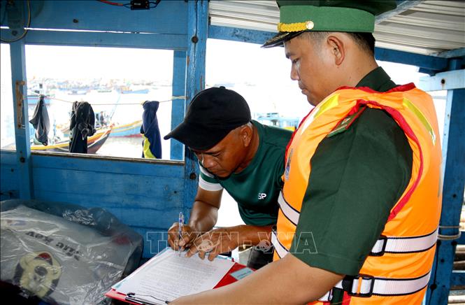 Cán bộ Đồn Biên phòng Thanh Hải hướng dẫn ngư dân ký cam kết không vi phạm IUU. Ảnh: Hồng Hiếu - TTXVN