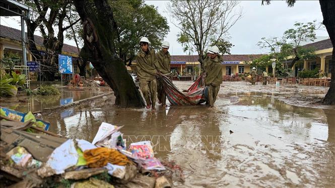 Các chiến sĩ quân đội hỗ trợ nhà trường thu gom, dọn dẹp sau khi nước lũ rút. Ảnh: Nguyên Dung - TTXVN