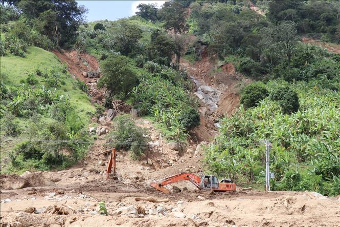 Công nhân dùng máy múc dọn dẹp đất đá sạt lở từ sườn núi tràn xuống tuyến tỉnh lộ ĐT707, đoạn qua thôn Bậc Rây 1 (xã Bác Ái Tây, Khánh Hòa). Ảnh: Nguyễn Thành – TTXVN