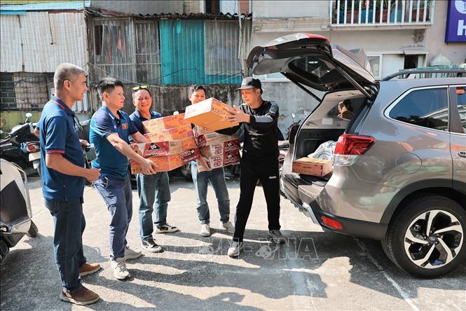 Anh Lỗ Minh Tuấn, Đội trưởng “Đội xe 0 đồng Hà Nội” cùng Tình nguyện viên tiếp nhận hàng hỗ trợ do các tổ chức, cá nhân quyên góp. Ảnh: Lê Đông - TTXVN