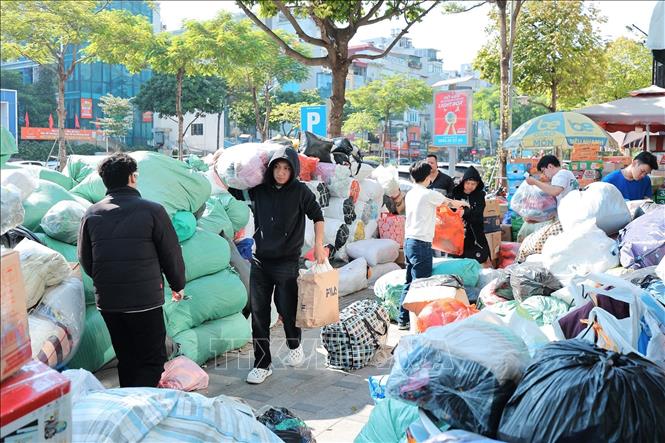 Tình nguyện viên phân loại và đóng gói quần áo để gửi tới đồng bào miền Trung tại điểm Ô Chợ Dừa. Ảnh: Lê Đông - TTXVN