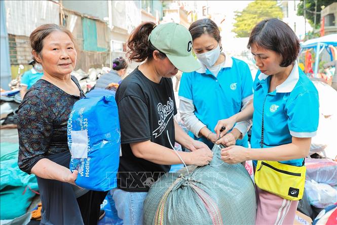 Tình nguyện viên phân loại và đóng gói quần áo để gửi tới đồng bào miền Trung tại điểm 105 Xuân La. Ảnh: Lê Đông - TTXVN