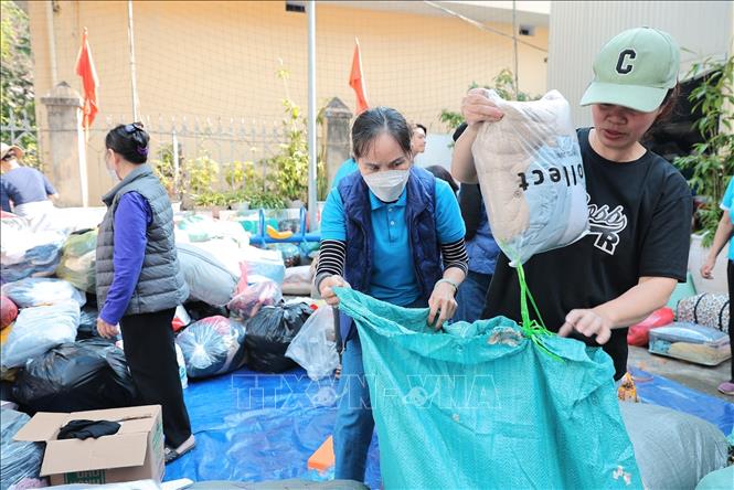 Tình nguyện viên phân loại và đóng gói quần áo để gửi tới đồng bào miền Trung tại điểm 105 Xuân La. Ảnh: Lê Đông - TTXVN