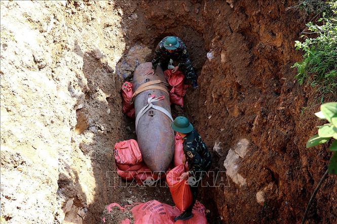 Lực lượng quân đội chèn các bao cát, đất cố định quả bom M118. Ảnh: Thanh Hải - TTXVN 