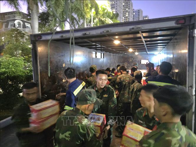 Military forces and volunteers load relief goods on trucks. VNA Photo: Thanh Vân