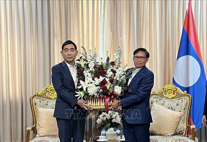 Đại sứ Phạm Việt Hùng (trái) tặng lãng hoa tới Đại sứ Lào Sisavath Inphachanh chúc mừng 50 năm Quốc khánh Lào. Ảnh: Đỗ Sinh - PV TTXVN tại Thái Lan