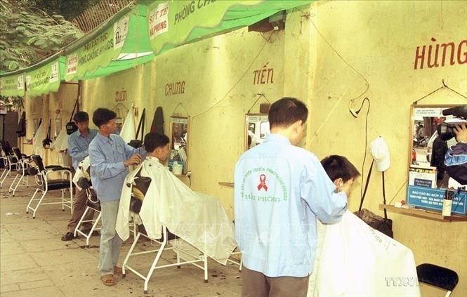 Một trong 10 điểm cắt tóc tuyên truyền phòng chống AIDS ở phường Cát Dài, thành phố Hải Phòng. Bằng hình thức này, mỗi năm các điểm cắt tóc giúp cho hàng vạn người hiểu biết về cách phòng tránh lây truyền HIV/AIDS. Ảnh: Hữu Oai - TTXVN