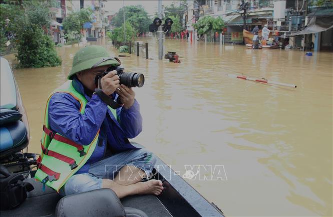 Phóng viên Đỗ Tuấn Anh, CQTT Lào Cai tác nghiệp tại khu vực ngập lụt do ảnh hưởng của cơn bão số 10 ở phường Yên Bái. Ảnh: TTXVN