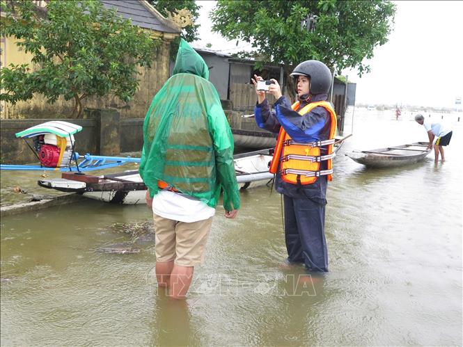 Phóng viên Mai Trang, CQTT Thông tấn xã Việt Nam tại Huế tác nghiệp tại rốn lũ phường Hóa Châu, thành phố Huế. Ảnh: TTXVN