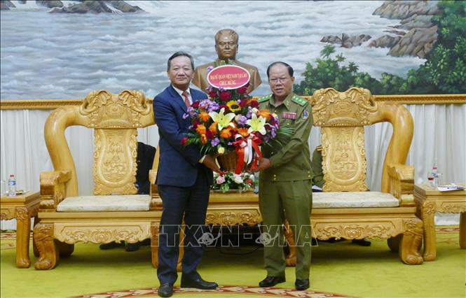 Đại sứ Việt Nam tại Lào Nguyễn Minh Tâm tặng hoa chúc mừng Bộ Công an Lào nhân dịp Kỷ niệm 50 năm Quốc khánh Lào và 105 Ngày sinh Chủ tịch Kaysone Phonvihane. Ảnh: Xuân Tú - PV TTXVN tại Lào